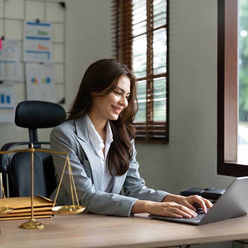 Mulher trabalhando feliz em seu laptop em um escritório corporativo