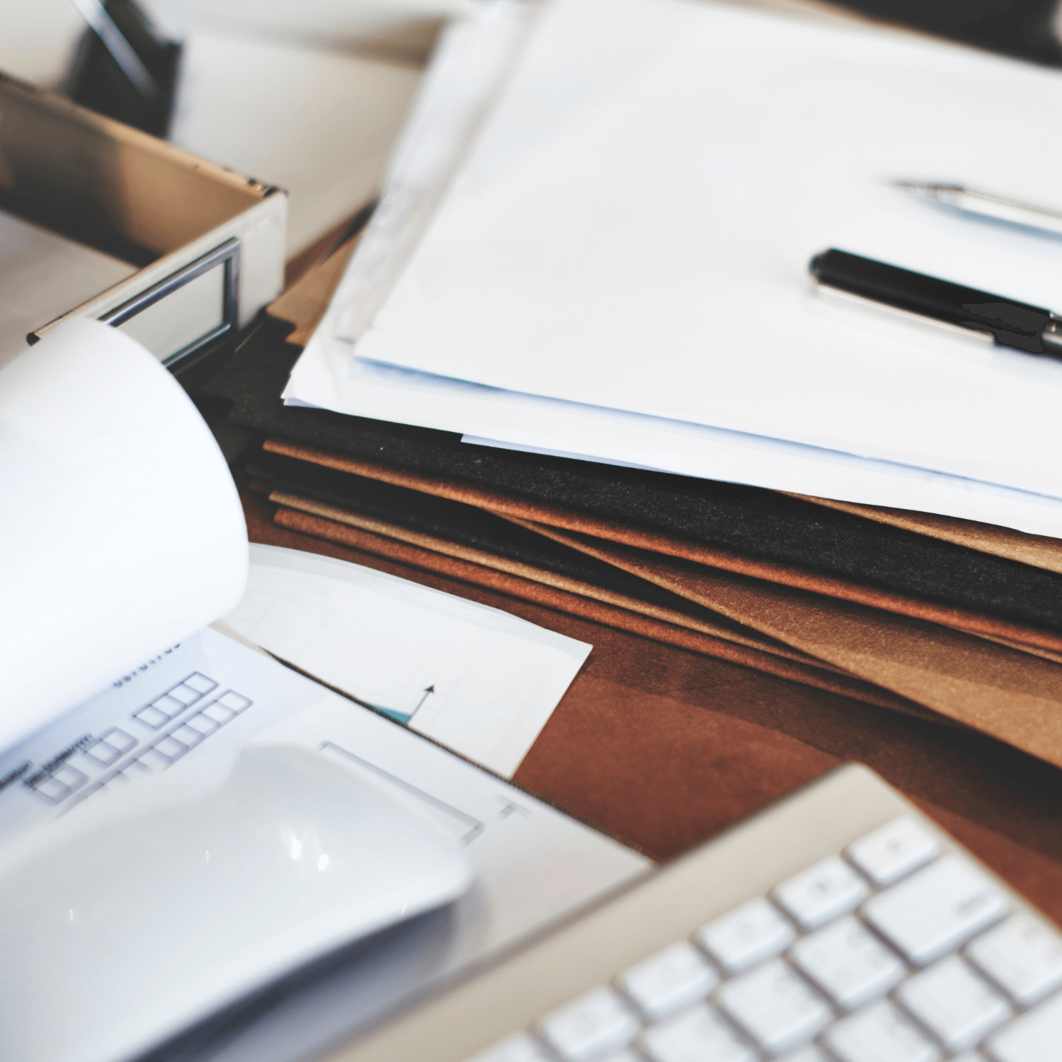 Documentos de produtos controlados em uma mesa de madeira ao lado de um teclado e mais pilhas de papéis