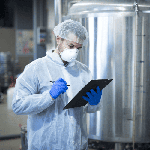 Técnico em química analisando uma prancheta ao lado de um tonel químico