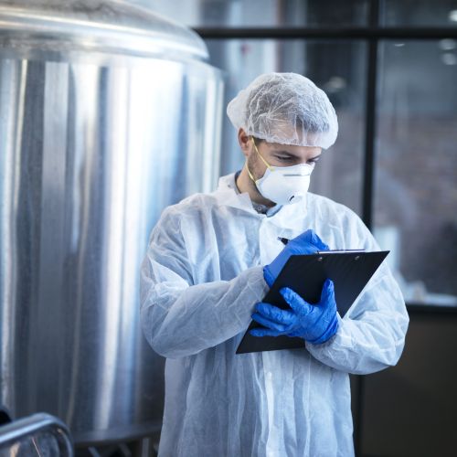 Especialista tecnólogo concentrado em terno branco controlando substâncias químicas